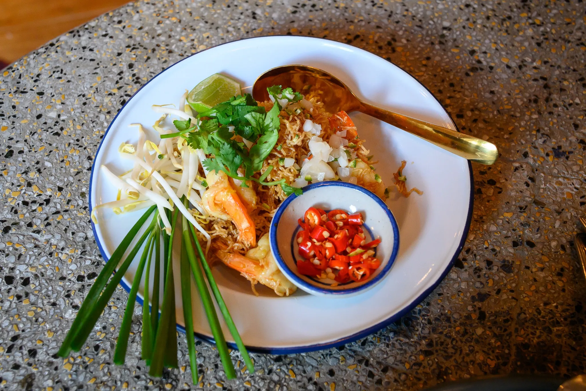 Shrimp pad thai with bean sprouts, chives, lime, and a dish of sliced chilies