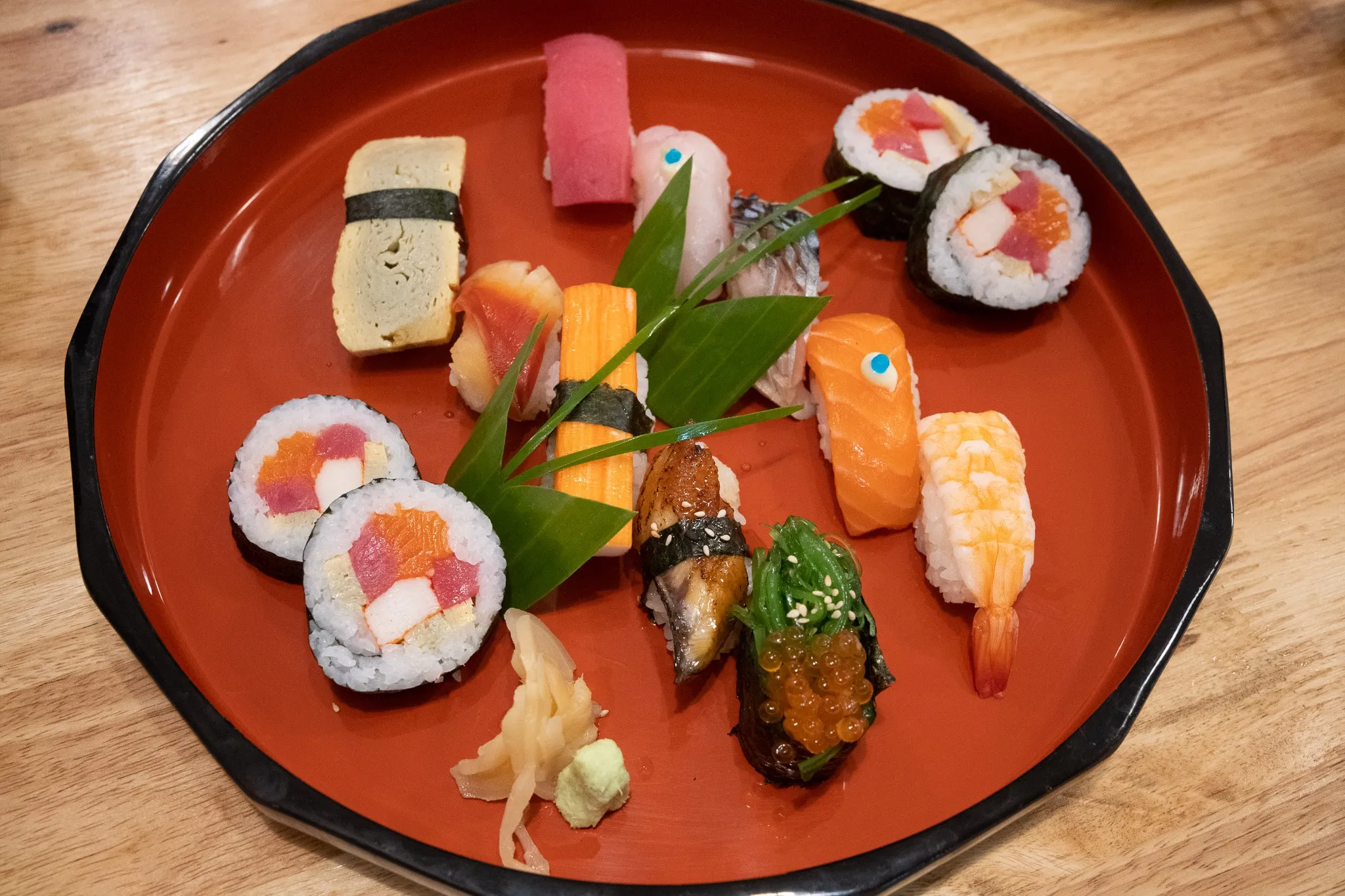 An assortment of nigiri and maki sushi on a round red lacquer tray