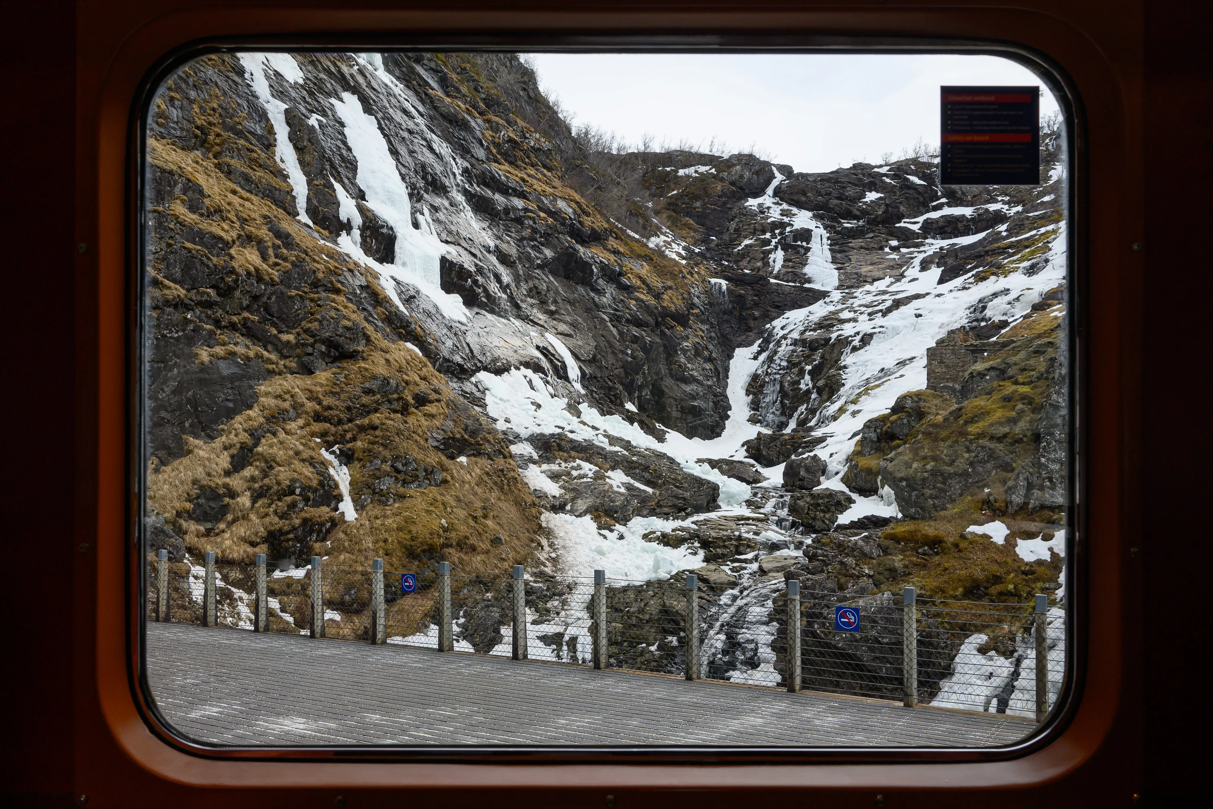 A waterfall and steep mountain slopes framed by a train window