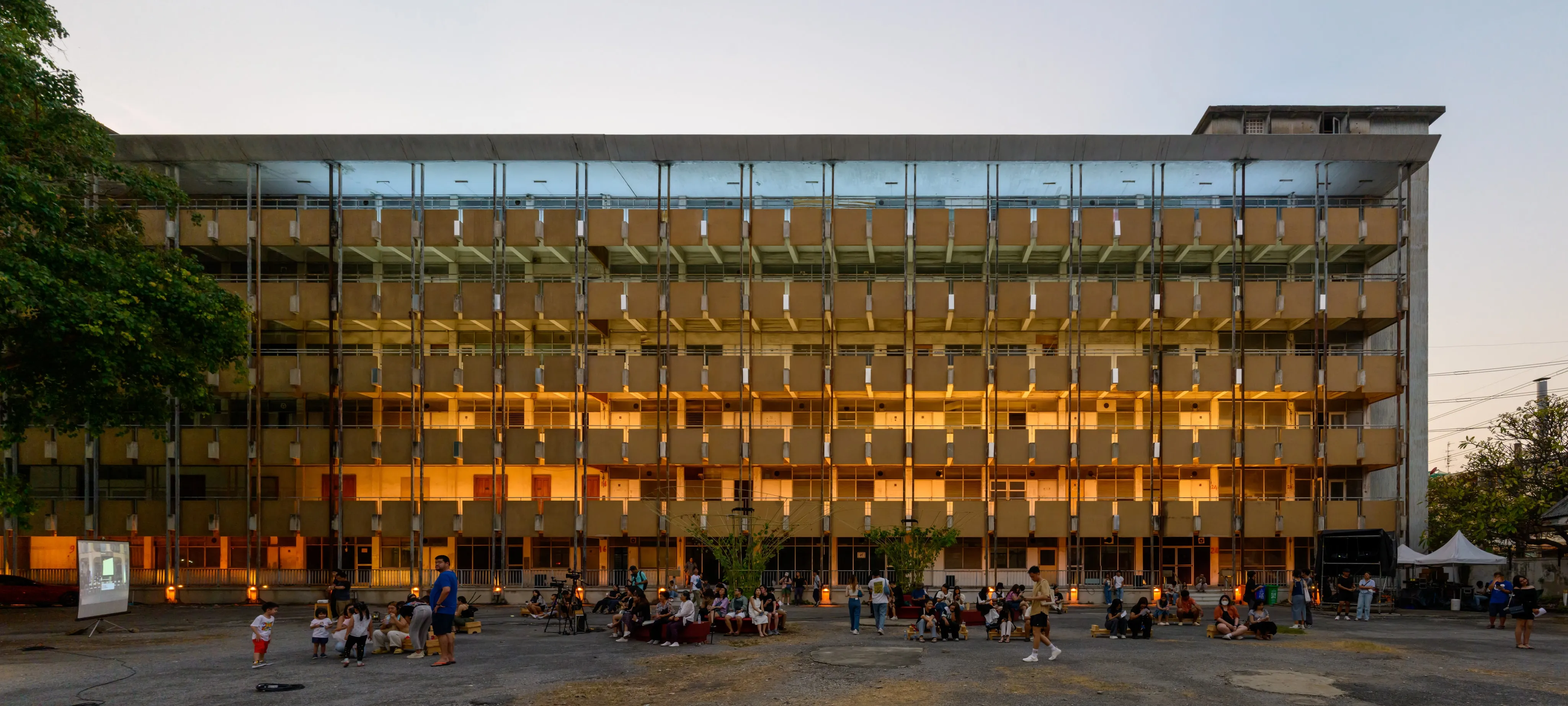A glass-fronted building glowing with warm light at dusk