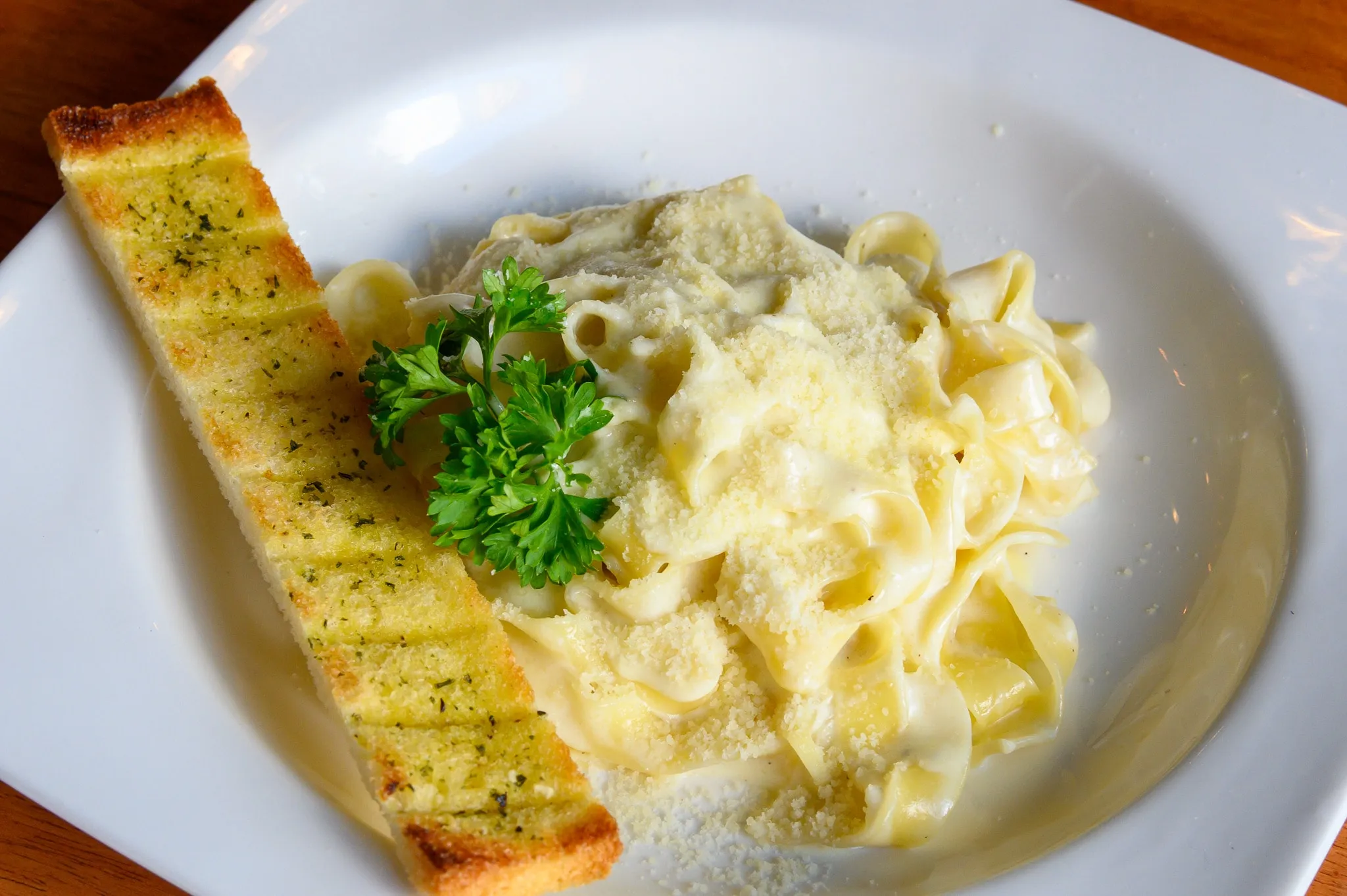 Fettuccine in cream sauce with parsley and a slice of garlic bread