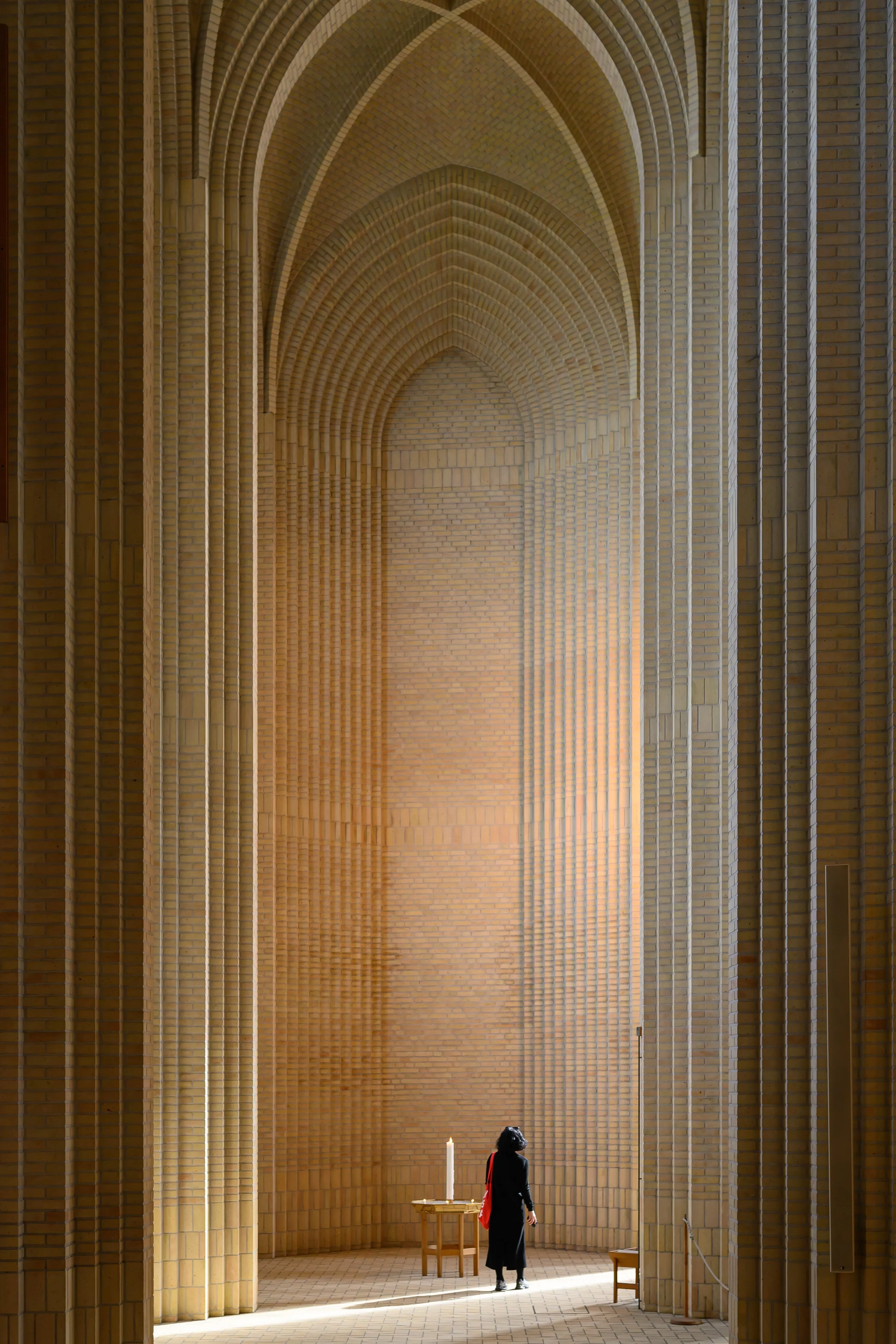 A lone figure beneath monumental brick church arches