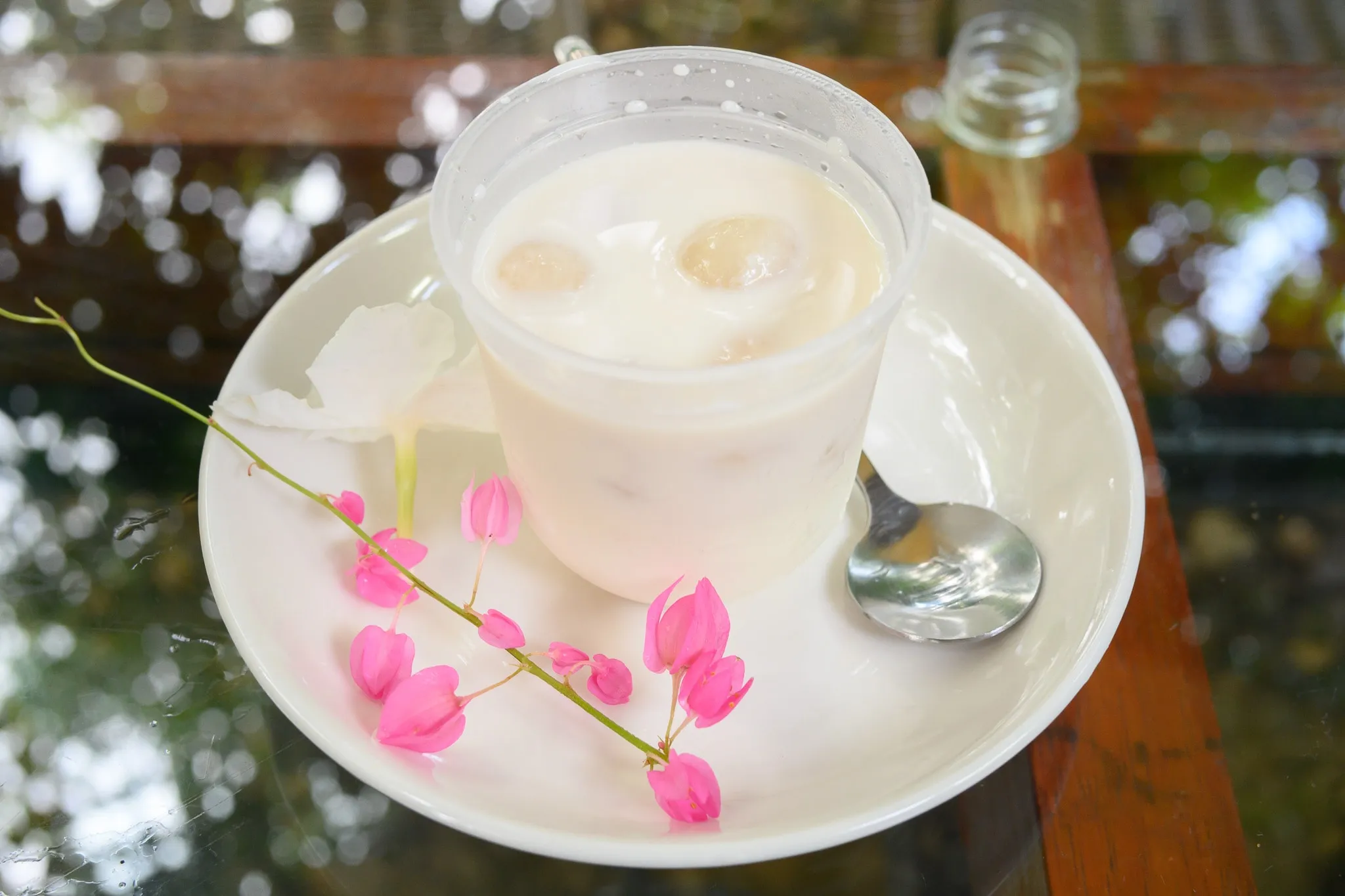 An iced coconut drink in a cup on a saucer decorated with pink coral vine flowers