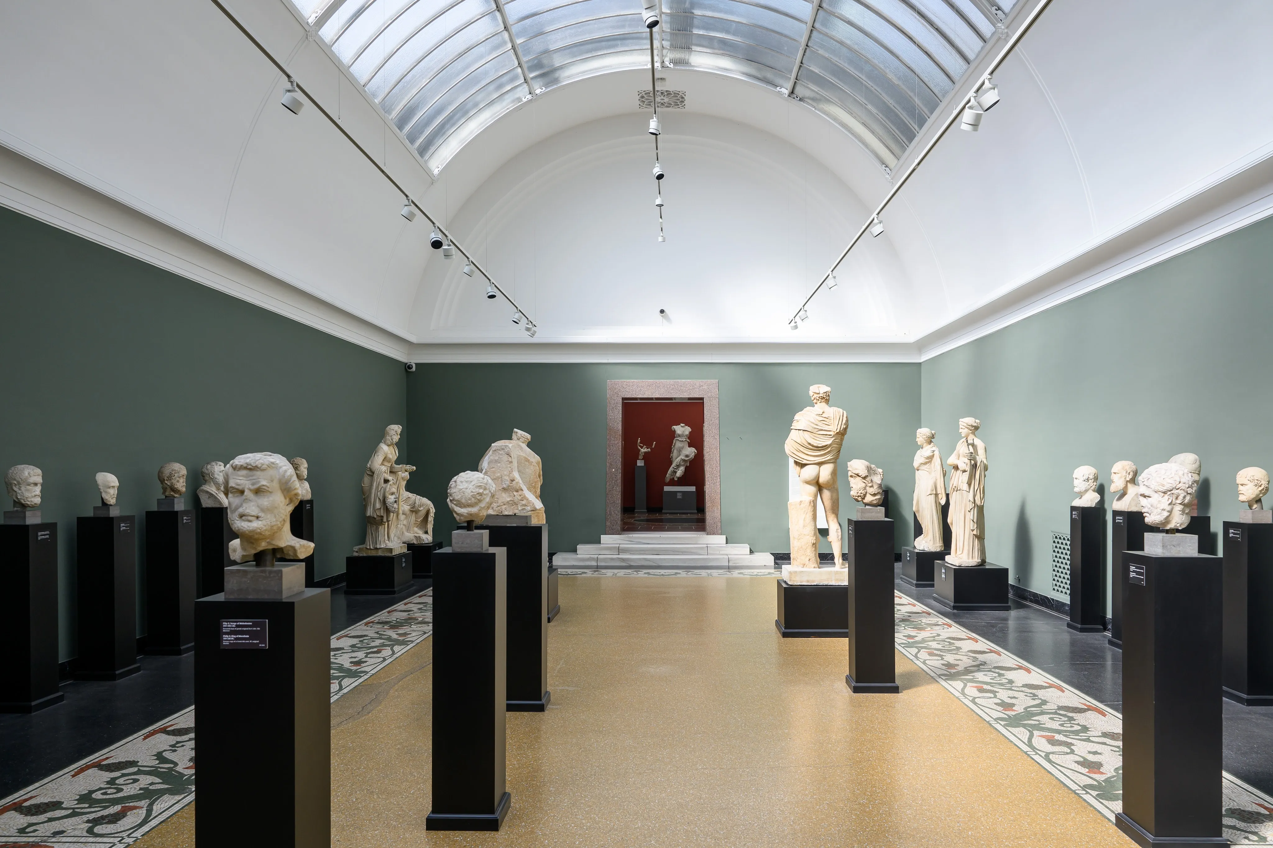 Sculptures displayed beneath a high museum ceiling