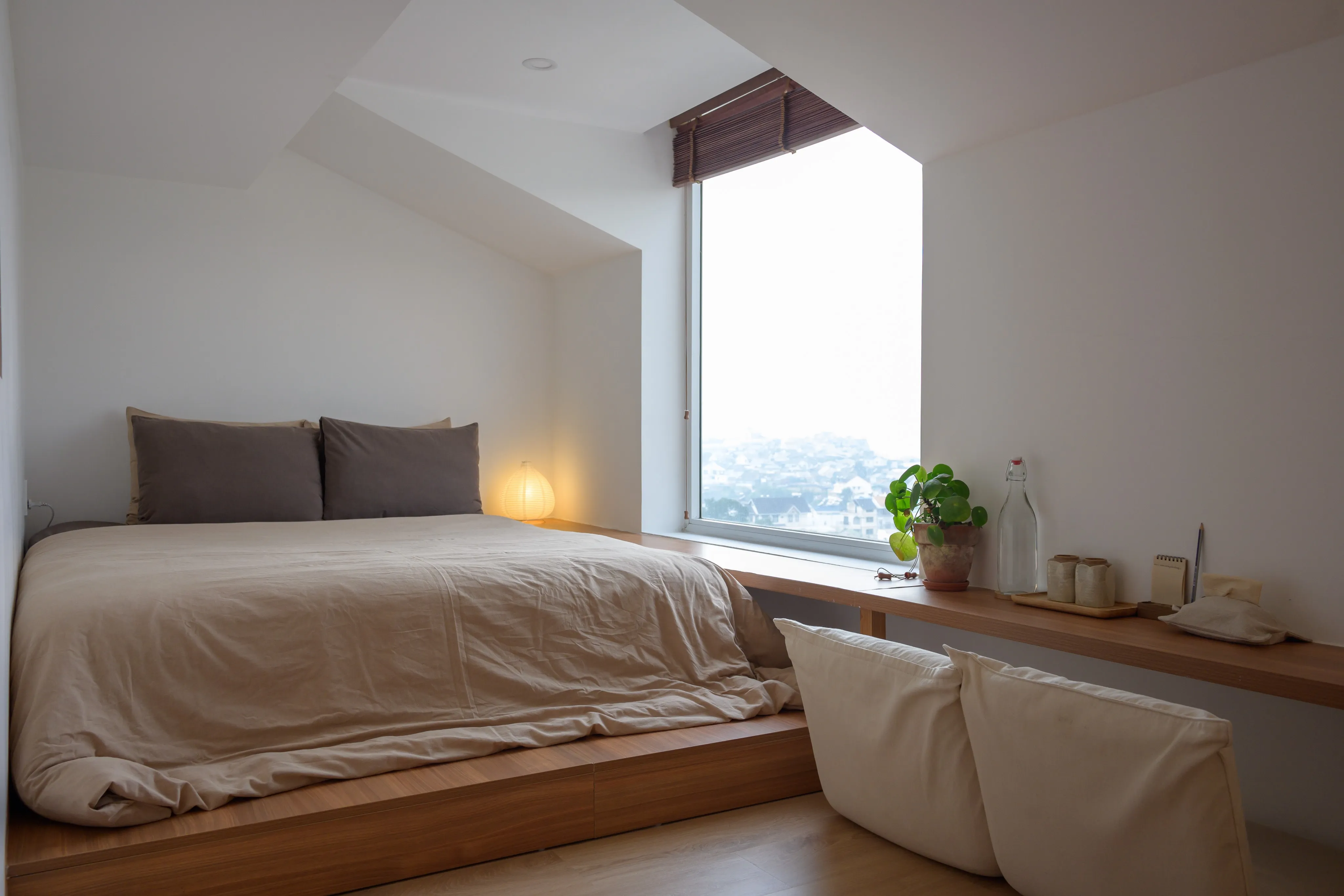 A minimalist bedroom with wooden floors and soft daylight