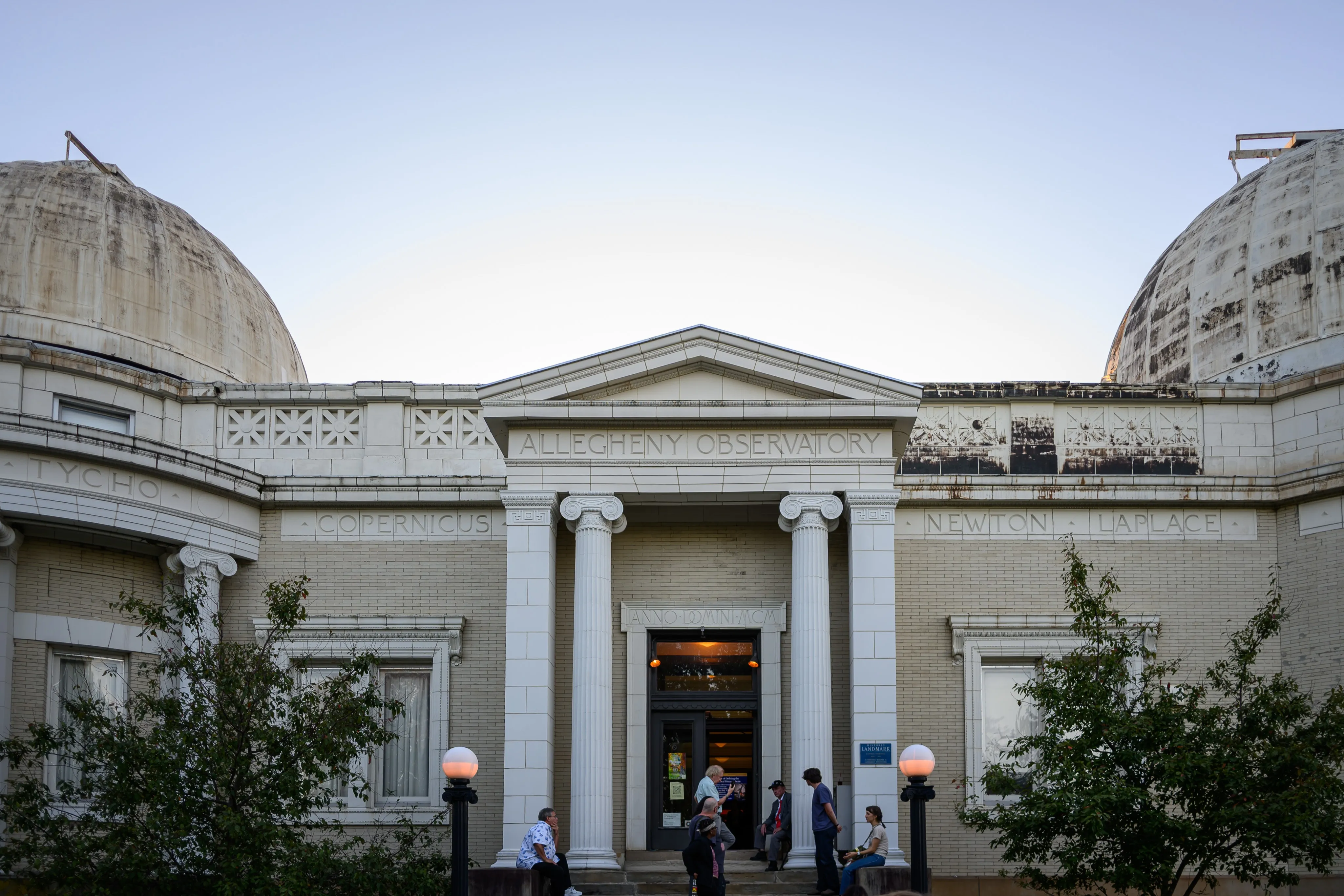 The front entrance of Allegheny Observatory framed by its two weathered domes, with visitors gathered outside.